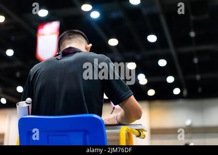 Blue chair of badminton referee with yellow colors near badminton net with blurred background in sport indoor stadium. Stock Photo