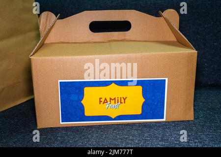 A brown takeout cardboard box with a 'Family Feast' sticker tag. Stock Photo