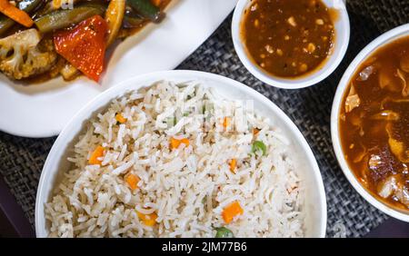 Top view of Vegetable Fried Rice in a white ceramic bowl on a table mat background with Indo-Chinese foods Stock Photo