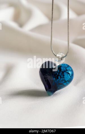 A closeup shot of a dark turquoise handmade glass heart shaped necklace on a white background Stock Photo