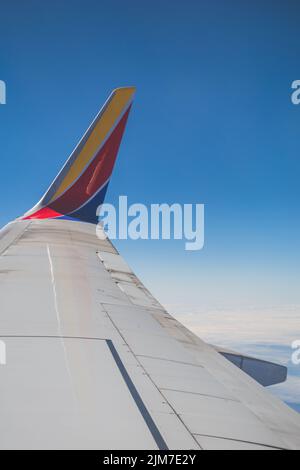 A beautiful view over the wing of southwest airlines 737-800 airplane against blue sky in bright sunlight Stock Photo