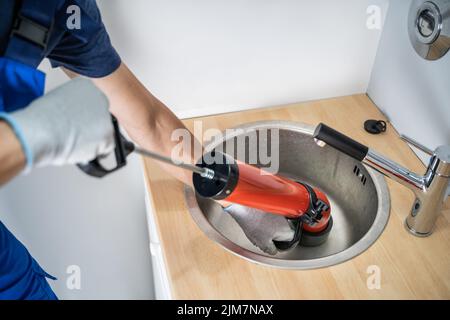 Plumber Cleaning Drain And Sink Using Pump Stock Photo