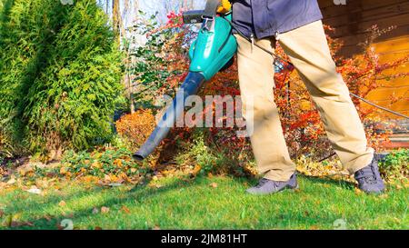 Garden tools for the care of the garden and the local area. Blower using process. The gardener holds a blower in his hands and cleans the lawn from fa Stock Photo