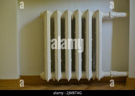 Pipes and a white heating radiator heat the room. heating season Stock Photo