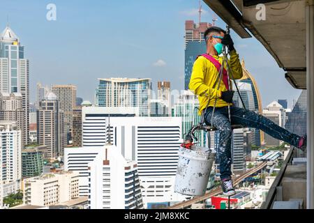 Thai workman repairing window in high rise building using rope and ...