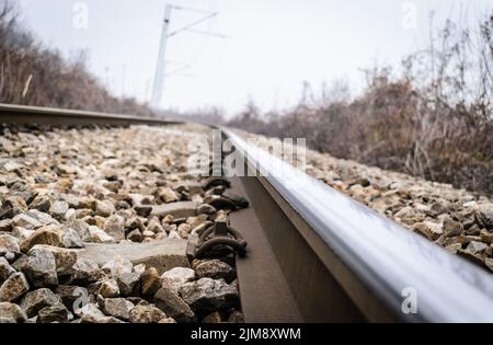 Scenic view of straight railway or railroad track receding into distance on foggy day. The concept of traveling by train. Stock Photo