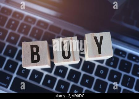 Wooden cubes with word buy on laptop keyboard. Online Shopping concept Stock Photo