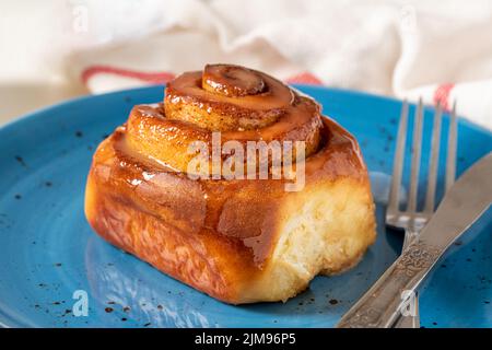 Freshly baked cinnamon roll on a blue porcelain plate Stock Photo