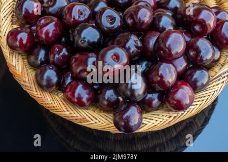 Close up of fresh ripe cherries , in a colorful wicker basket of fresh ripe cherries , in a colorful wicker basket Stock Photo