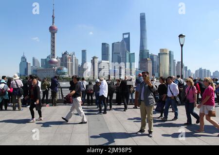 Crowd of tourists walking by the Bund and taking pictures of Shanghai's classic skyline - Pudong business district (China). Stock Photo