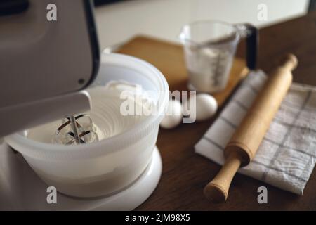 Modern mixer mixing whipped cream on wooden table with ingredients close up. Wooden table. Vertical. Stock Photo