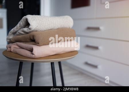 Stack of cozy knitted sweaters on a wooden table. Retro style. Warm concept Stock Photo