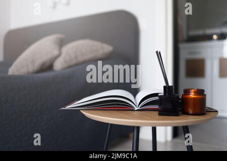 An open magazine on the coffee table with a candle and an aroma diffuser in the bedroom. Home cozy photography. Stock Photo