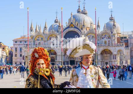 Venice, Italy - February 28, 2022: Couple dressed in traditional costumes, in St. Marks Square, part of the Venice Mask Carnival, Veneto, Italy Stock Photo