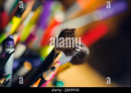 Dishevelled paintbrush in a box of coloured pencils Stock Photo