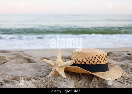 Straw hat and starfish on beautiful sand by the sea Stock Photo