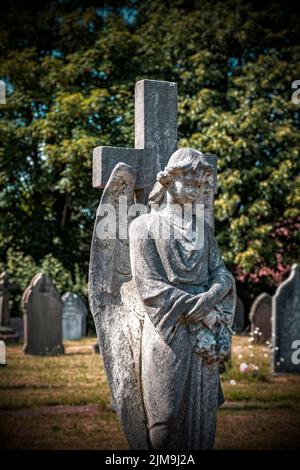 Statue of an angel with cross in cemetery UK Stock Photo