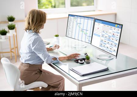 Employee Using Schedule Calendar On Computer Screen Stock Photo