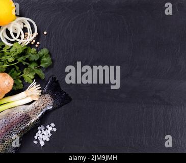 Fresh whole fish and herbs displayed on natural slate stone background Stock Photo