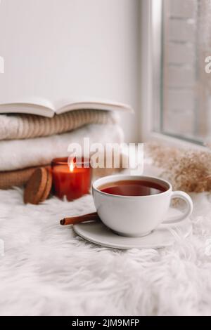 Beautiful autumn composition with burning candle and cup of tea on window sill Stock Photo