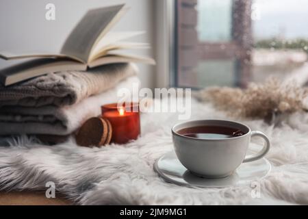 Beautiful autumn composition with burning candle and cup of tea on window sill Stock Photo