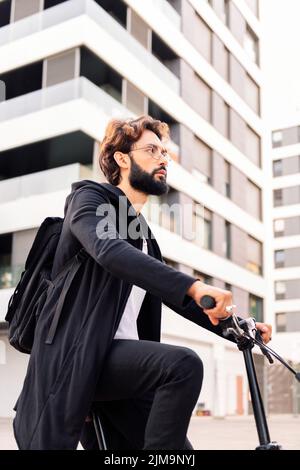 stylish young bearded man riding his bike through the city, concept of urban lifestyle and sustainable mobility, copy space for text Stock Photo