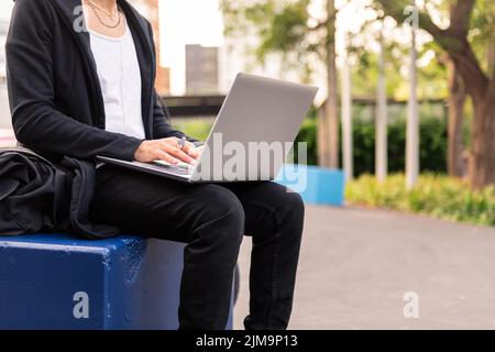 unrecognizable young student working on his laptop computer at the university campus, concept of technology and education, copy space for text Stock Photo