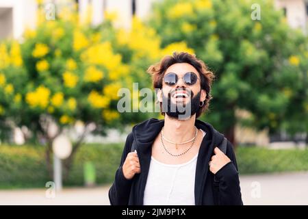 stylish young student with beard and sunglasses laughing happy looking at camera, concept of youth and urban life style, copy space for text Stock Photo