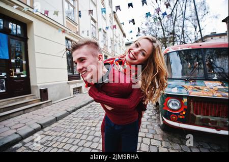 Young beautiful stylish fashion couple in a red dress in love story at the old city, having fun background old retro vintage bus Stock Photo