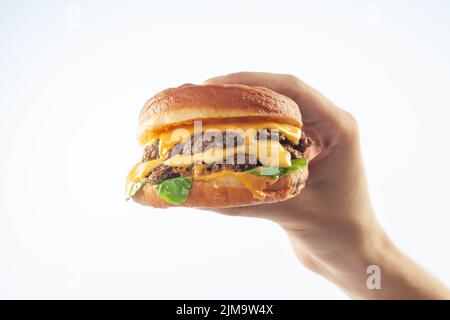 Hand holding a gourmet brioche cheese burger isolated on a white background Stock Photo