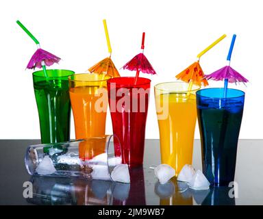 Colored glasses with cocktails and ice cubes on a white background Stock Photo