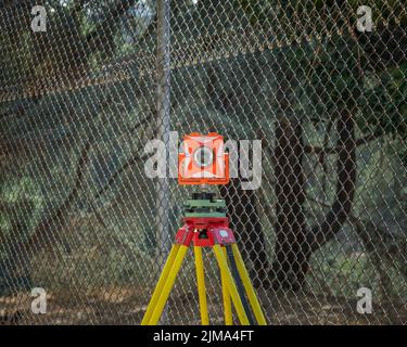 An orange and white transit level sits atop a yellow and red tripod at Lake Hollywood in Los Angeles, CA. Stock Photo