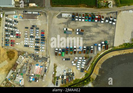 Top down aerial view of lifting dump trucks and work vehicles in dirt lot outdoors Stock Photo
