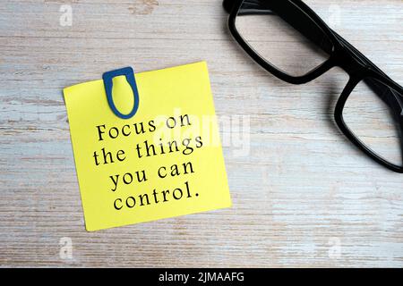 Motivational quote on sticky yellow note on wooden desk - Focus on the things you can control. Stock Photo