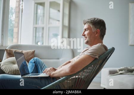smiling man with a laptop sitting in an armchair . Stock Photo