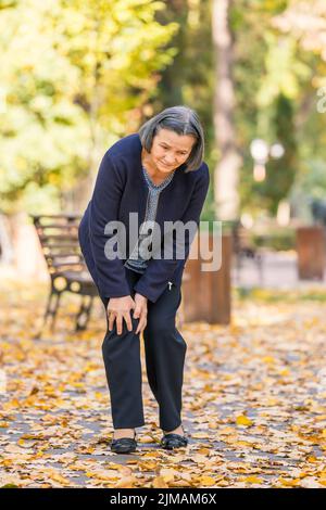 Senior woman having knee pain walking in park Stock Photo