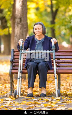 Senior woman with walker getting up and walking outdoors Stock Photo