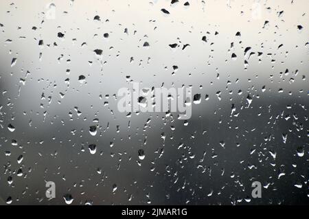 Abstract photo background. Rain drops on window. Selective focus, rainy city background. Water drops on glass. Rainy weather, blur wallpaper.  Stock Photo