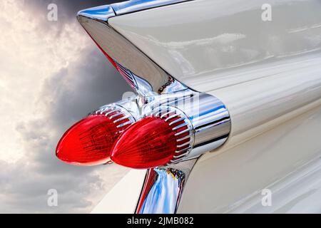 Red conical tail lights on the white fin on the stern of an American classic road cruiser Stock Photo