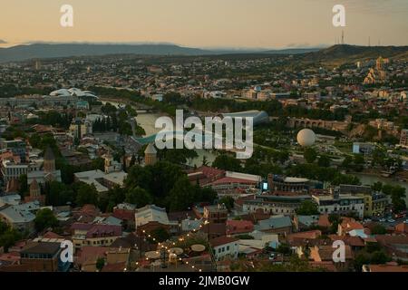 Tbilisi, Georgia sunset Panoramic view from top of fortress of Narikala showing the bridge of peace, Rike Park, Kura River and Holy Trinity Cathedral Stock Photo