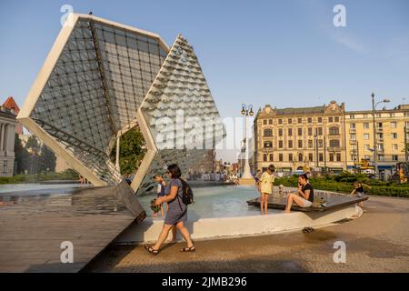 Happy children cooling themselves down with water from the fountain in the Plac Wolnosci square Stock Photo