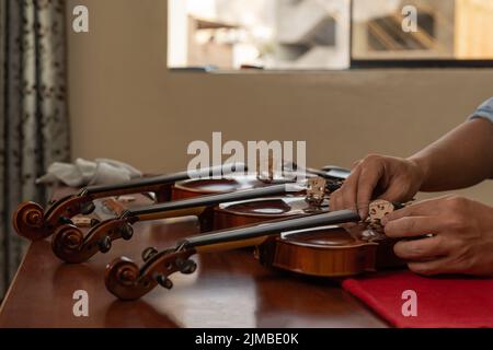 Three violins being fixed in a musical instrument repair workshop Stock Photo