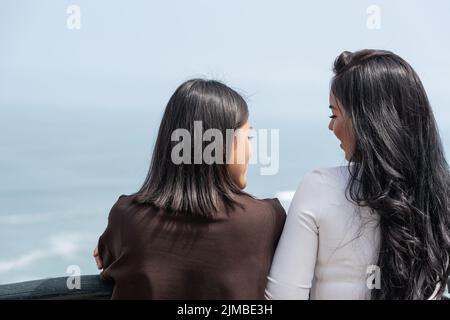 Back of two women gazing the horizon from the viewpoint of Miraflores in Lima, Peru Stock Photo