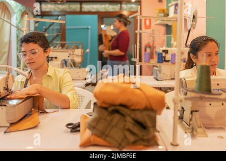 Three multiethnic women working in a sewing workshop Stock Photo