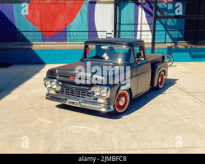 old black Ford F100 pickup truck Custom Cab Flareside bed Twin Beam circa 1960 parked in a warehouse yard. Classic car show. High angle. Copyspace Stock Photo