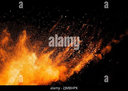 Abstract orange powder explosion on black  background. Freeze motion of orange dust particles splash Stock Photo