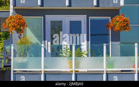 Glass balconies of modern apartment building in residential area. Balcony of modern condo with plants on sunny day. Nobody, street photo Stock Photo