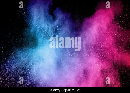 Multicolored powder explosion on black background.Blue pink dust particles splattered. Stock Photo