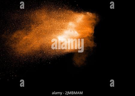 Orange color powder explosion on black background. Orange particles splash. Stock Photo