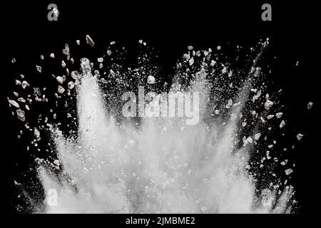 White powder with small stones explosion on black background. Small granite rock stone splash agains Stock Photo